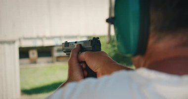 Nişancı kulaklık takarak atış poligonuna nişan alıyor ve ateş ediyor..