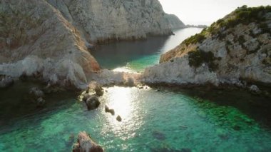 Yunanistan 'da yaz günü kayalıklar arasındaki turkuaz sulara yansıyan güneş ışığı.