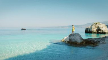 Kefalonya 'da açık denizin kayalık sahillerinde yürüyen kadın Yunanistan.