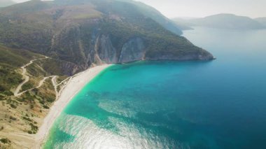 Yazın Kefalonia adasındaki Myrtos Sahili 'nde zümrüt suları boyunca kıvrılan uzun beyaz kumsal..