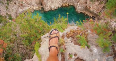 Kayalık uçurumun kenarında duran adam Capri yaz gezisinde turkuaz körfeze bakıyor..