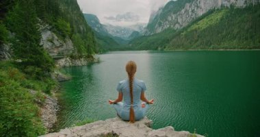 Huzurlu kadın Avusturya 'daki Gosausee gölünde meditasyon yapıyor..