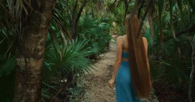 Meksika 'da bir mezarlık yakınında palmiye ağaçlarıyla tropikal orman yolunda yürüyen bir kadın..