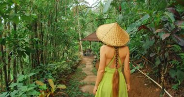 Bali 'deki Tegelalang pirinç teraslarının yakınındaki ormanda yürüyen bir kadının arka görüntüsü.