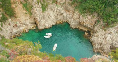 Capri kıyı şeridi yakınlarındaki bir yaz gününde kayalık bir turkuaz koyda yüzen tekneler..