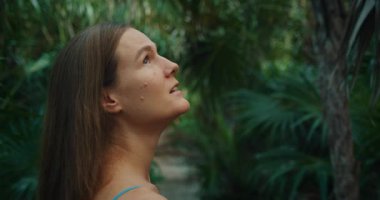 Kadın yukarı bakıyor ve Yucatan Meksika 'da yoğun yeşilliklerle çevrili tropikal ormanda yürüyor..