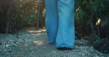 Güneş ışığı altında çıplak ayakla ormanda yürüyen kadınların yakınlaşması..