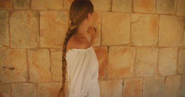 Maya tapınağında yürüyen bir kadın arkeolojik harabelerde taş duvarlara dokunuyor..