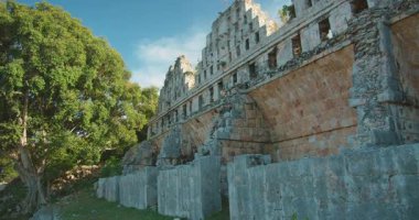 Uxmal arkeolojik alandaki ağaçlarla çevrili bir Maya kemer yapısının kalıntıları.