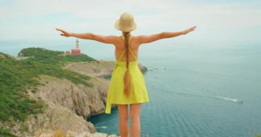 Capri 'deki deniz fenerine tepeden bakan kadın kolları açık duruyor..