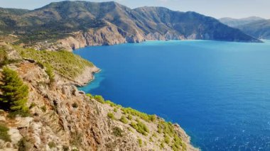 Mavi denize bakan kayalık uçurum terasında yürüyen adam ve Yunanistan 'daki engebeli dağlar, Kefalonia.