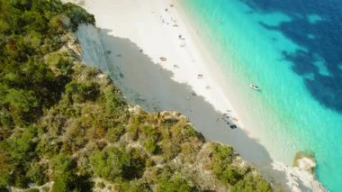 Kadın, Kefalonia 'da plajın yukarısında uçurumun kenarında duruyor ve turkuaz deniz Yunanistan' da.