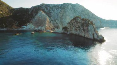 Engebeli kireçtaşı kayalıkları günbatımında sakin turkuaz denizle buluşuyor..