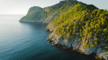 Kefalonia uçurumlarındaki çam ormanı gün batımında derin mavi İyon Denizi ile buluşuyor..