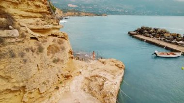 Yaz mevsiminde Kefalonia 'da kayalık sahildeki merdivenlerden bir kadın denize giriyor..