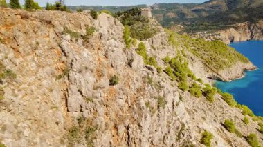 Yunanistan 'ın Kefalonya kıyı köyü ile sarp kayalıkların üzerindeki Assos şatosu ve çam ormanının taş kalıntıları.