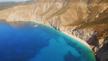 Yunanistan 'ın Kefalonia adasında sarp kayalıklarla çevrili beyaz kumlu plajın hava manzarası.