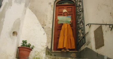 İtalya 'nın Amalfi kasabasında kırsal bir kapının önünde elinde harita tutan bir kadın var..