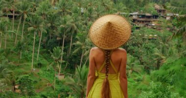 Hasır şapkalı kadın Tegallalang 'daki yemyeşil palmiye vadisine hayran Bali' deki pirinç teraslarına.