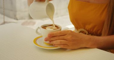 Yaz günü Amalfi Kafe 'de kapuçinoya çay tabağıyla süt dökülüyor..