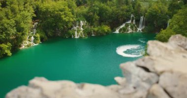 Hırvatistan 'daki Plitvice Gölleri Ulusal Parkı' ndaki sık yeşillikler arasında zümrüt göl ve çağlayan şelaleler.