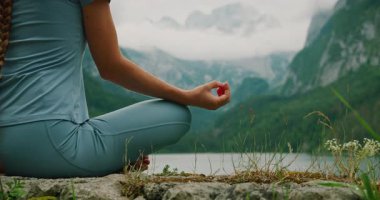 Arka planda bir dağ gölü tarafından çerçevelenmiş yoga Mudra pozu veren bir kadının eli. Yaz Gosau Avusturya..