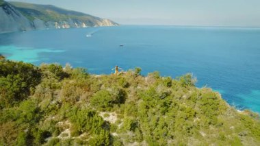 Kefalonya 'da yaz mevsiminde engin mavi denize bakan bir uçurumda duran kadın görülüyor..