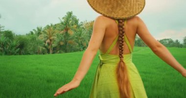 Bali turu sırasında yemyeşil pirinç tarlalarını ve yeşil tropik manzaraları keşfeden bir kadın..