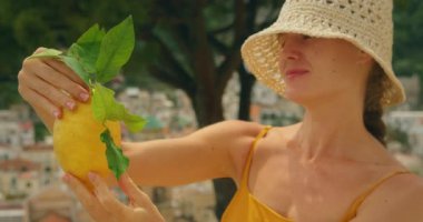 Limona gülümseyen bir kadının yakınındaki Amalfi Sahili yamaç kasabasının önünde..