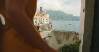 Altın elbise, gölgeli bir terastan sahil kasabasına hayran kalarak akıyor.