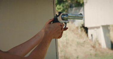 Atış talimi sırasında dışarıya gümüş tabanca doğrultmuş bir kadın..