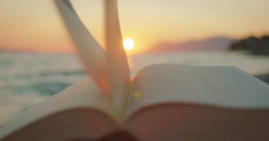 Gün batımında denizin üzerinde sayfalarca meltem esintisi eşliğinde İncil 'in yakın görüntüsü..