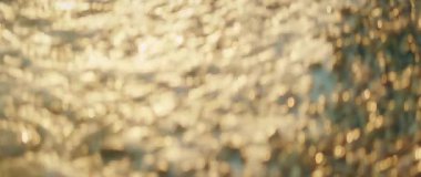 Yaz günbatımında sakin deniz dalgaları ve su yüzeyinden yansıyan altın güneş ışığı..