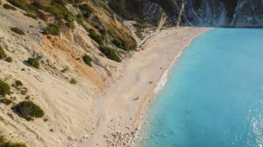 Yunanistan 'da sarp kayalıkların yakınında güneşlenen kumsallar ve altın çakıl taşları.