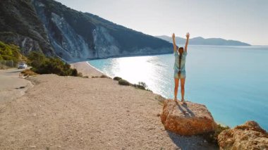 Yunanistan 'ın en dramatik Myrtos Sahili' nde kadınlar uçurumun kenarında kollarını kaldırıyor.
