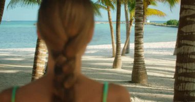 Örgülü bir kadın kumsalda denize doğru yürüyor ve Meksika 'nın Yucatan Yarımadası' ndaki okyanusa bakıyor..