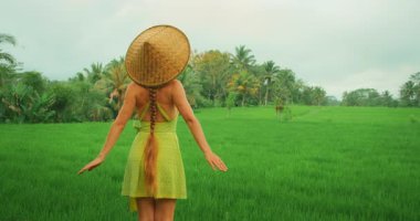 Bali gezisi sırasında tropikal bölgede yeşil pirinç tarlasından hoşlanan şapkalı kadın..