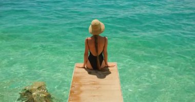 Mayo ve hasır şapkalı kadın, yazın Hırvatistan 'da açık denizde bir iskelede dinleniyor..