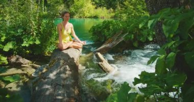 Plitvice Gölleri Ulusal Parkı 'ndaki yemyeşil ormanlarda meditasyon yapan kadının yakın görüntüsü.