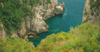 Capri 'deki bir yaz gezisi sırasında yukarıdan görülen berrak mavi suyu olan kayalık bir koy..