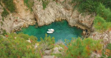 Capri Adası, İtalya 'da güneşli bir yaz gününde gizli bir kayalık koyda tekneler yüzer..