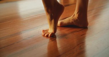 Bir kadın dans ederken ayak parmaklarıyla tahta zeminde dengede durur..