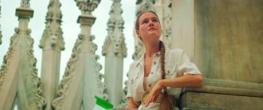 Kadın yazın Milano katedralinin çatısındaki süslü kulelerin arasında geziyor..