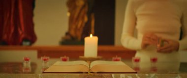 Kilisede dini bir tören sırasında mum yakan kişiyle mermer sunakta İncil 'i açın..