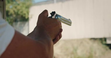 Erkek eğitmen, atış poligonunda tabanca kullandığını gösteriyor..