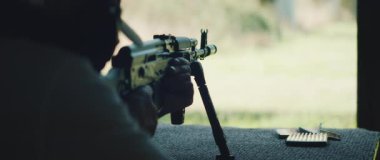 Nişancı dışarıda atış talimi yaparken tüfeği hedef alıyor..