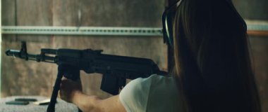 Kadın menzilde kulaklık takarken siyah tüfeği hedef alıyor..