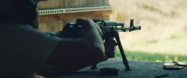 Adam eğitmen atış talimi sırasında tüfeği yedek kulübesinde hazırlıyor..