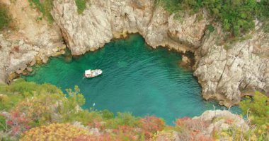 Capri İtalya 'sında kayalık kayalıklarla çevrili sakin turkuaz koyda yüzen tekne..