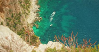 Güneşli Capri 'de kayalık kıyı şeridi yakınlarında sığ turkuaz sularda yüzen tekneler..